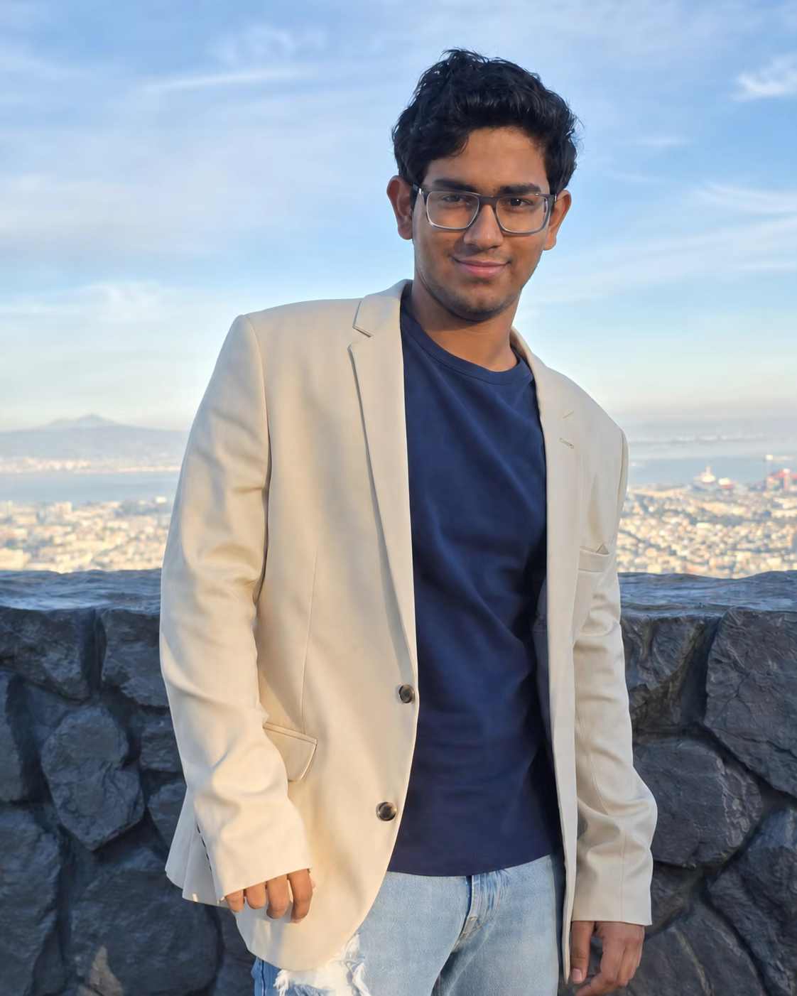 Aditya Das at a scenic overlook wearing a cream blazer
